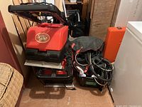 Photo showing two Mega Star carpet cleaner machines and upholstery attachments stacked together with various cords and hoses.