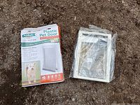 Photo showing the PetSafe pet door frame and flap next to its box, both items appear new and unused.