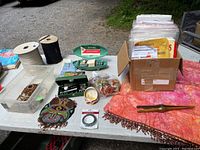 Full lot on table including Singer buttonholers, beaded bag, beaded lampshade, elastic rolls, curtain rings, sewing patterns, and table runner.