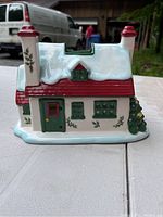 Side view of ceramic Spode Christmas cottage showing red roof, green door and window with holly decorations and Christmas tree detail