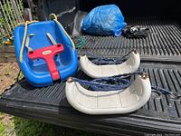 Blue baby swing with red front harness and two white plastic swings with blue chains placed on truck bed