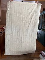Full view of the thick quilted duvet showing its size and off-white color with faint floral embroidery.