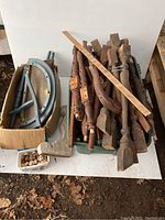 Photo depicting a green suitcase or container with mahogany stained wooden legs and spindles with turned carved details, alongside the box with blue painted parts and small wooden knobs.