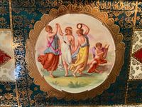 Close-up of dessert plate showing hand-painted classical figures with gilt border on teal ground
