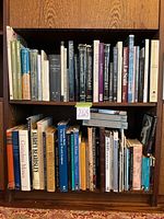 Two-tier wooden bookshelf filled with art books across top and bottom shelves