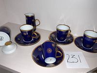 Four espresso cups on matching saucers with creamer pitcher and sugar bowl with lid arranged