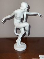 Front-left view of white porcelain nude figurine showing pose and circular base