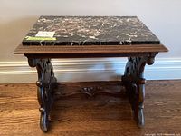 Front view of the end table showing marble top and carved wood base