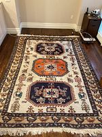 Full view of carpet laid on hardwood floor showing overall design and fringe.