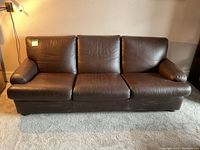 Front view of dark brown leather three-seat sofa showing overall condition