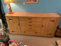 Front view of wooden cabinet with drawers and side compartments showing overall design and wear.