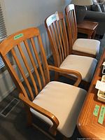 Photo showing two armchairs and one side chair in a dining room setting, highlighting wood finish and beige cushions.