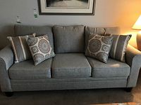 Front view of gray three-seater sofa with four decorative cushions