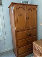 Front view of the tall pine dresser showing two cabinet doors and three drawers with brass hardware.