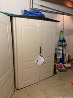 Front view of assembled shed showing double doors, handle, and hanging tag.
