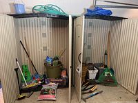 Two open plastic sheds filled with various long-handled gardening tools, bags of soil or fertilizer, and gardening accessories.