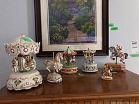 Wide view of the lot on a wooden surface showing multiple musical carousels and horse figurines.