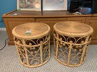 Two round rattan side tables shown side by side with woven tops and scroll detail framework.