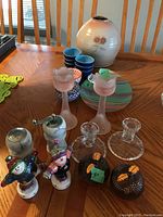 Full lot view showing salt and pepper shakers, pink candleholders, pottery vase, ceramic bowls, and glass plate