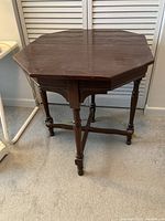 Octagonal wooden side table with four legs and casters, showing the foldable leaves in the closed position.