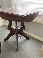 Side view of the Eastlake side table showing the carved details on the legs and apron, and the overall shape.