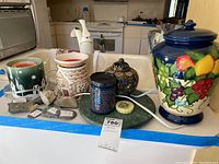 Full view of assorted candle warmers, hand painted urn, stones, and other home decor items grouped on a table.