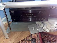 Front view of Onkyo TX-SR601 AV Receiver showing display and controls, powered on with channel information visible. Remote control and Wii game accessories visible nearby for scale.