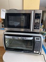 Photo of Black & Decker microwave placed on top of Oster toaster oven showing both appliances with front view and control panels.