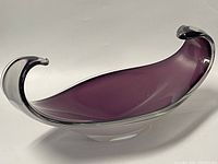 Angled side view showing purple freeform blown glass bowl with clear glass edges and curved ends.