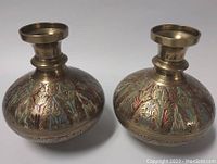 Front view of both brass vases showing bulbous body with colorful floral and leaf engravings.