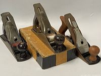 Two vintage hand planes, one Stanley and one Footprint, with original box in middle showing wear.