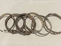 Top view of six silver plated and metal bangles showing varied decorative designs and textures.