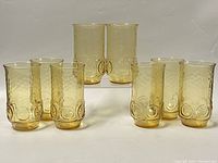 Eight honey gold glass tumblers arranged in three groups, showing the color and bubbles pattern.