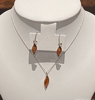 Full view of the silver chain necklace with amber pendant displayed on a white bust along with the matching amber drop earrings.