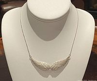 Front view of the silver angel wings pendant on the choker necklace displayed on white bust form.