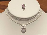 Front view of silver necklace with heart pendant and teardrop pendant displayed on bust form.