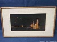 Front view of framed sailboat artwork showing colorful sailboats and birds against dark background.