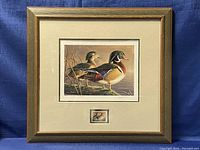 Framed limited edition print showing two wood ducks by James Hautman with stamp mounted below