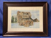 Framed limited edition print depicting a rustic house in winter, showing the entire artwork and frame.