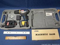 RYOBI cordless drill in gray plastic carrying case with charger. Includes wooden and plastic rulers and cardboard box labeled Magnetic Base.