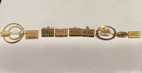 Full set of vintage C-I-L cufflinks and pins laid out in a line on white background showing all items in the lot.