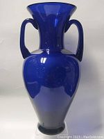 Front view of vintage large cobalt blue glass vase showing flared rim and dual curved handles.