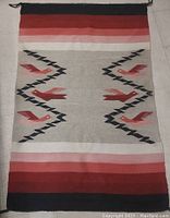 Full view of the Navajo rug showing symmetrical bird motifs and color bands.