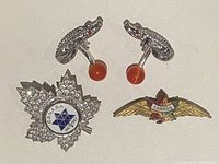 Photo showing two RTT London crocodile cufflinks with orange spherical ends and two Canadian pins, one shaped like a maple leaf with blue star emblem and the other a winged badge with maple leaf and Canada banner.