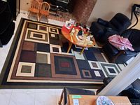 Full view of the area rug laid out in a room showing the overall geometric pattern and color scheme.