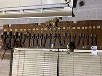 Set of metal automotive punch tools arranged on a pegboard above a window blind, sized from 3/8 inch to 1-3/4 inch.
