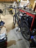 Full view of the black Phenom 29-inch mountain bike parked indoors among other equipment.