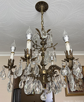 Chandelier hanging from ceiling showing full structure, six arms and crystal pendants.