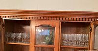 Wooden cabinet displaying crystal wine glasses, crystal flute glasses and art glass decanter.