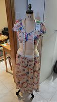 Full front view of canvas-covered dress form with cast metal base and wheels